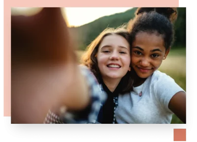 Two teens posing for a selfie outside in low muted warm light