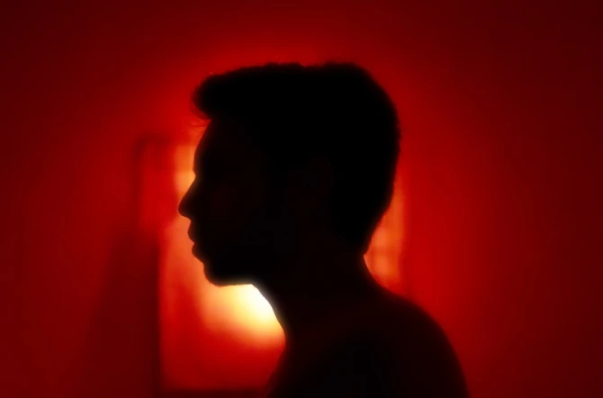 Outline shadow of teenage boy on angry red background
