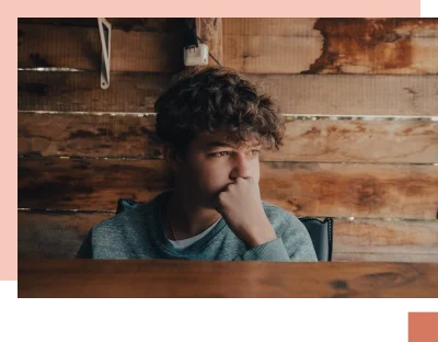 Nervous teen covering mouth with hand looking out in front of wooden background