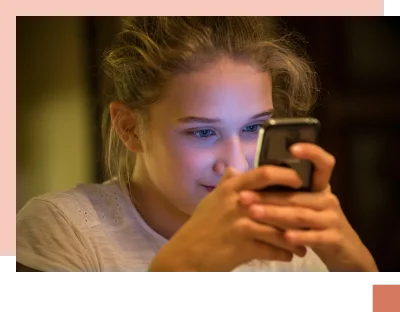 Teen stares into phone with screen light reflecting in her eyes and face