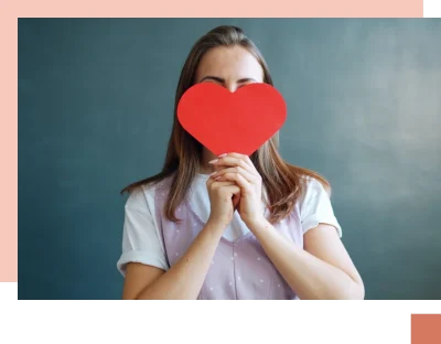 Teenage girl covering face with red heart