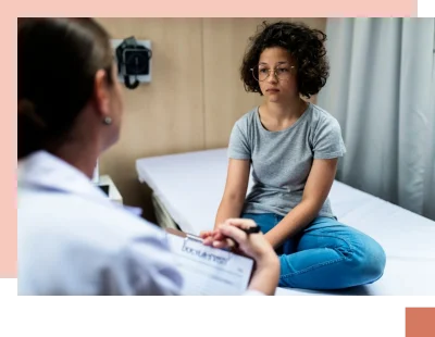 Girl sitting on bed with sad expression listening to doctor