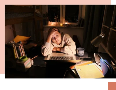 Teen overwhelmed and tired surrounded by books at night in bedroom