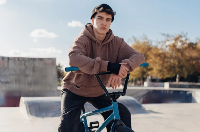 teen on BMX bike wearing hoodie in skatepark