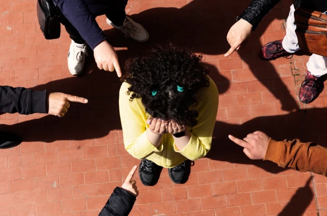 Group pointing at child in middle of circle in playground with orange asphalt shot from above