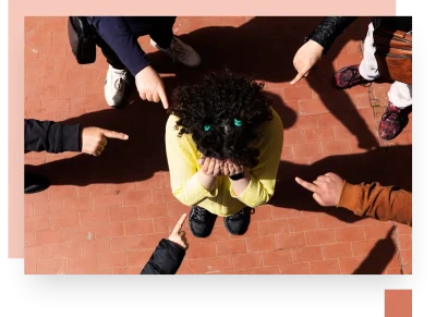 Group pointing at child in middle of circle in playground with orange asphalt shot from above
