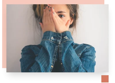 Teenage girl hiding side of her face with both hands wearing denim shirt