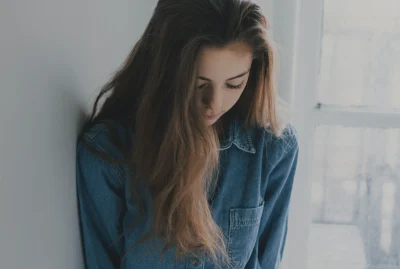 Young girl with dark hair looking down with sad expression