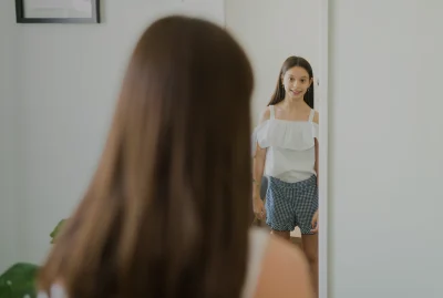 Young girl looking at body reflection in mirror