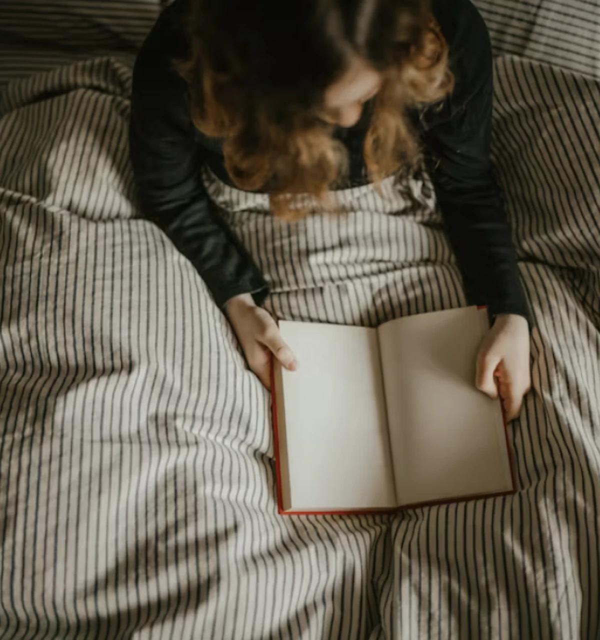 Girl-reading-holding-open-journal-in-bed