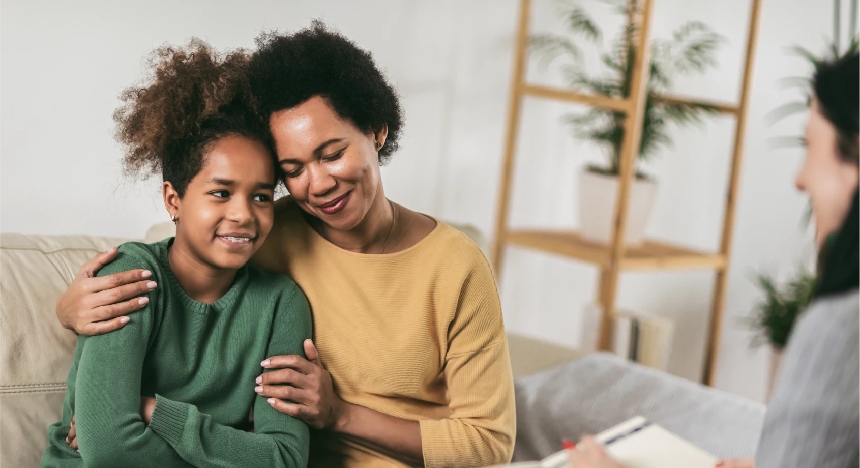 Parent-and-child-hug in open light contemporary room with therapist at side of shot