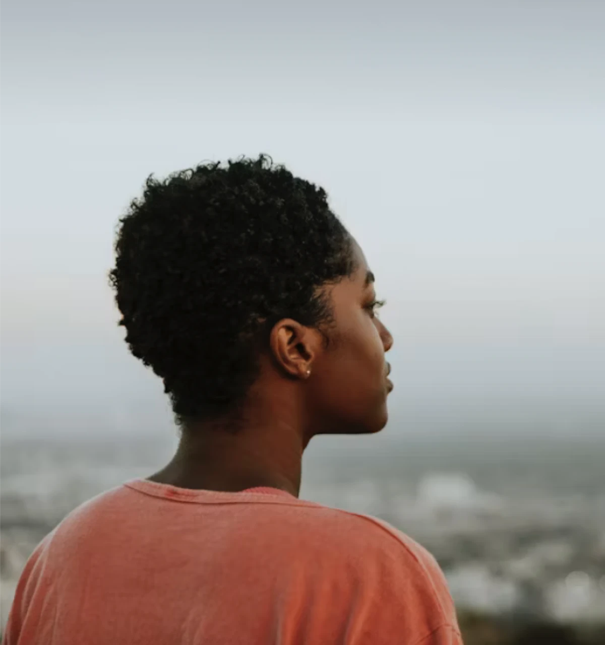 Young-male-looking-out-at-dreary-sea-with-red-top