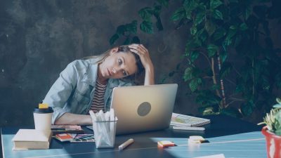 A woman appears stressed while working on laptop