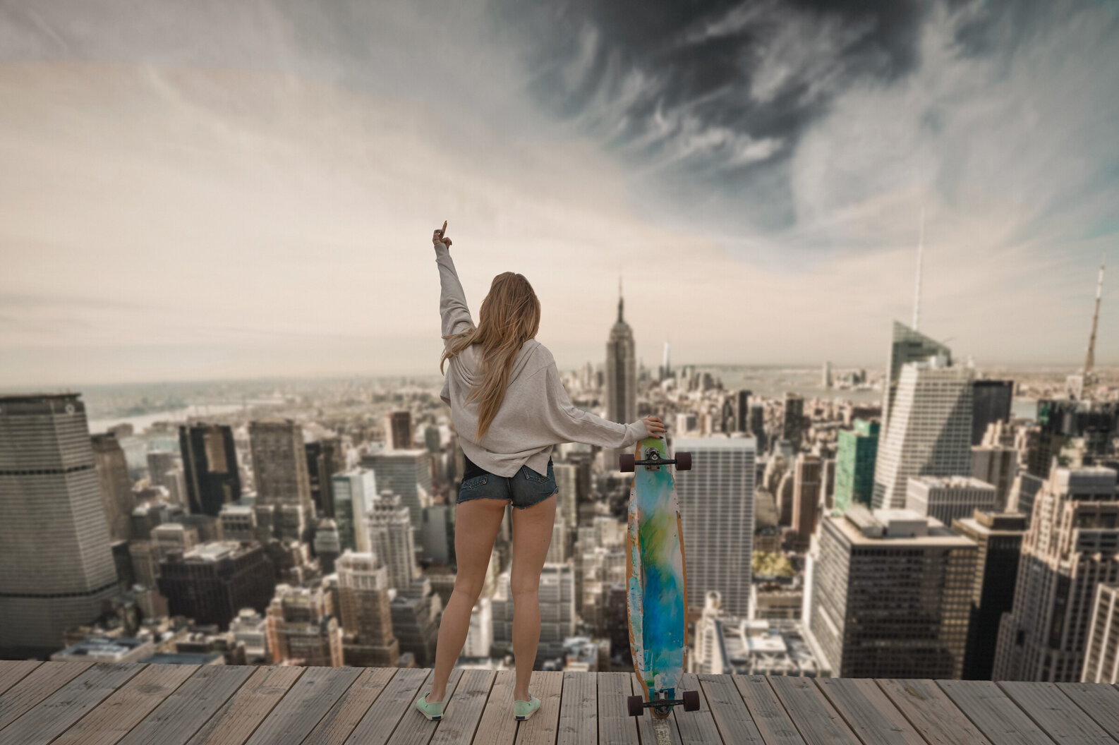 rebellious teen looking over NYC skyline with skateboard and short wants raising her middle finger up at the sky