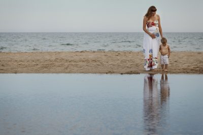 Mother and child at beach touching tummy's