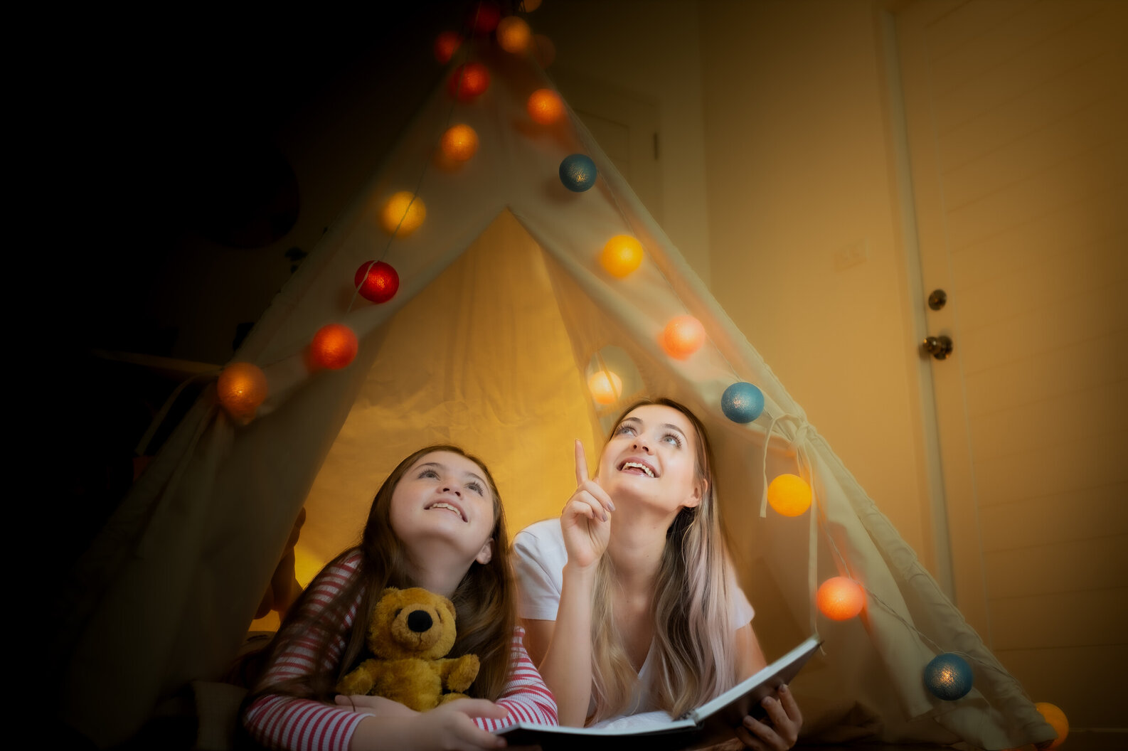 Mum and daughters reading in kids base with coloured lights