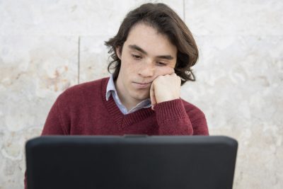 teen behind laptop watching screen