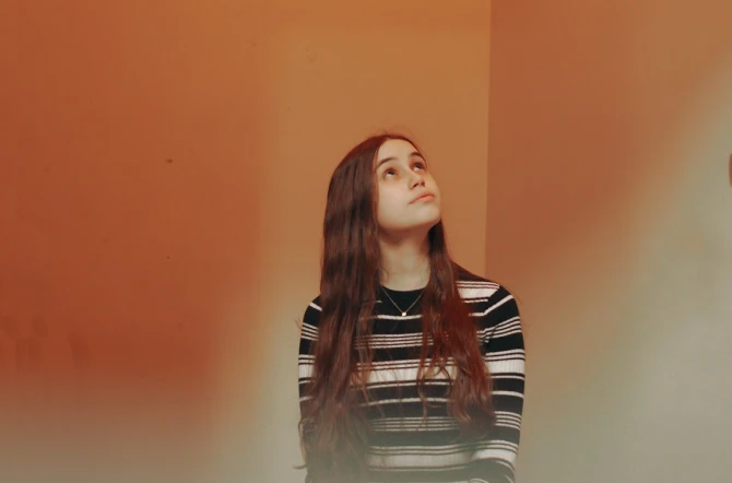 Teenage girl anxiously looking up with red background